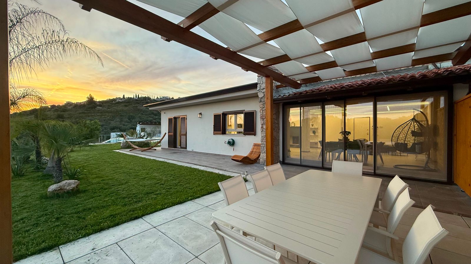 Pergola con tavolo da pranzo e tramonto sul giardino