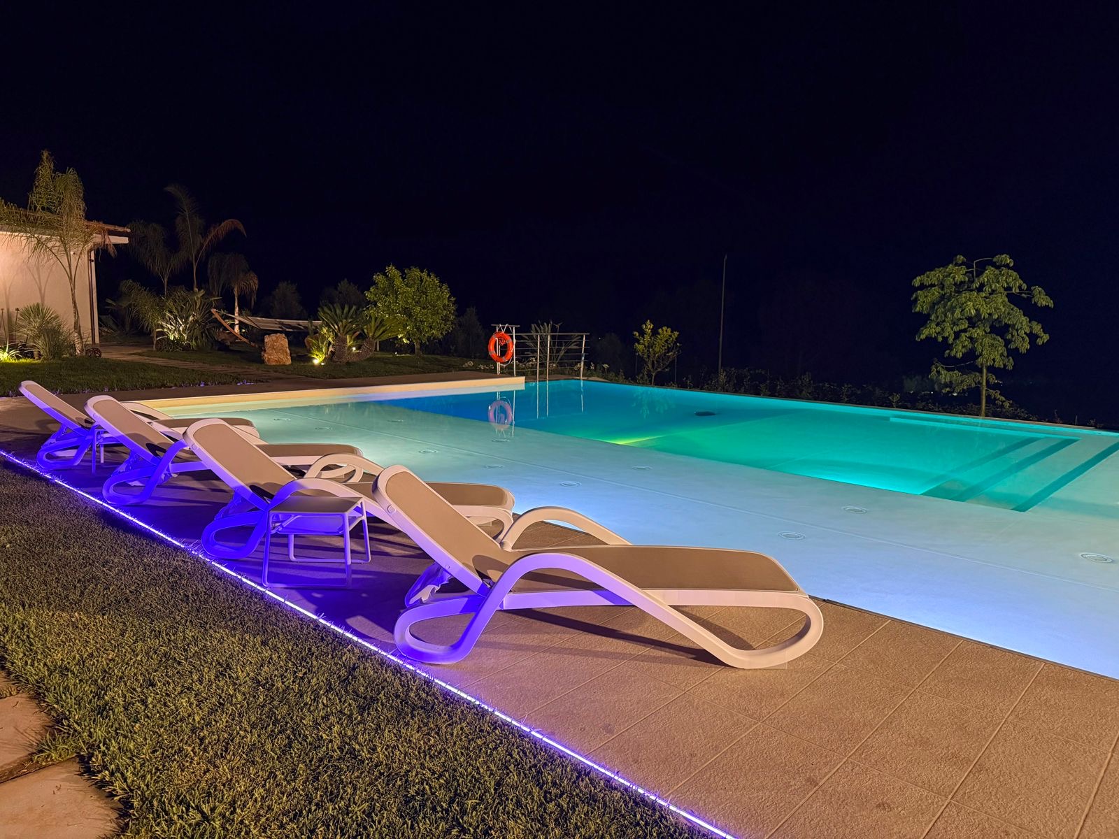 File di lettini accanto alla piscina di notte