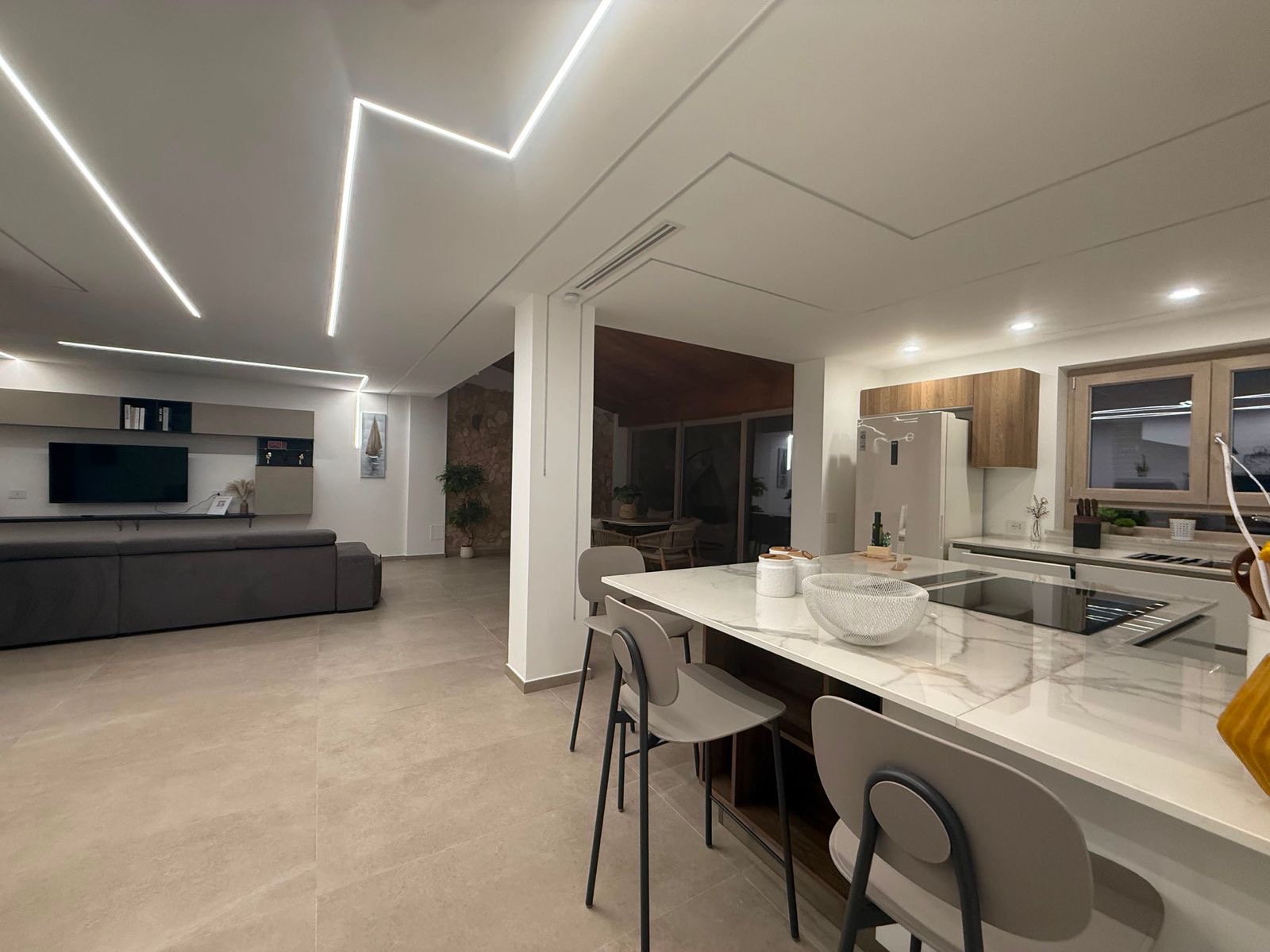 Living e cucina open space con illuminazione LED geometrica