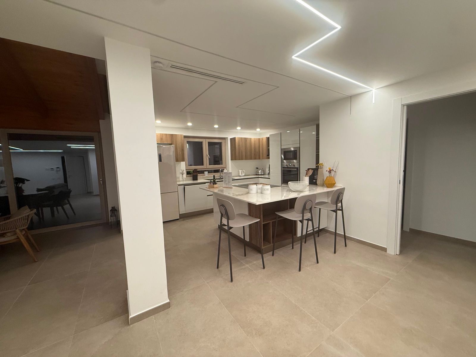 Cucina con isola in marmo, ante in legno e zona pranzo