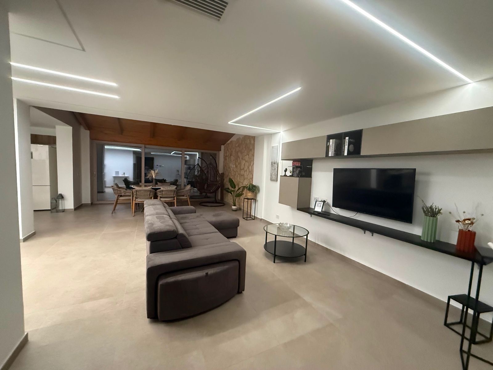 Ampio soggiorno con TV, LED a soffitto e zona pranzo