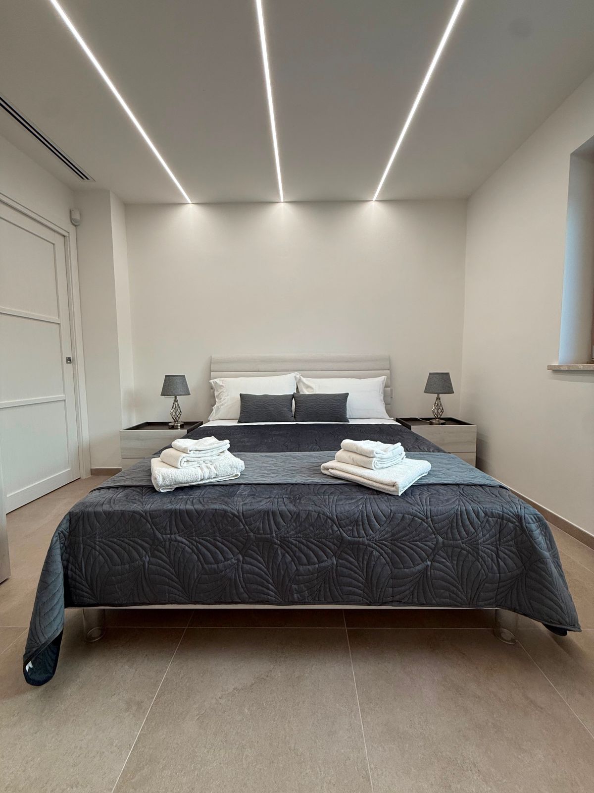 Camera matrimoniale con copriletto scuro e LED a soffitto
