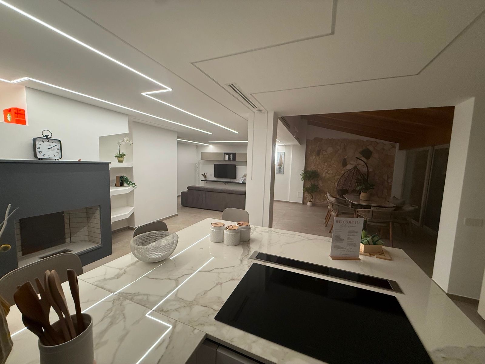 Cucina con isola in marmo, camino e LED a soffitto
